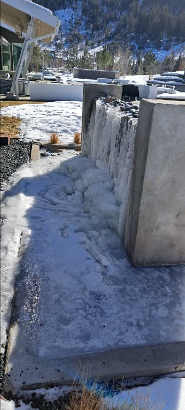 Heavy ice covering the basin and side of a raised water feature in snowy conditions