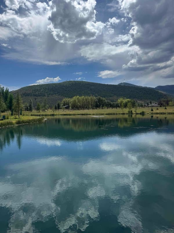 Open water on the Park City pond reflecting clouds and surrounding hills