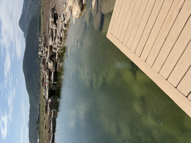 Constructed pond with natural stone edging and a rock waterfall beside a deck