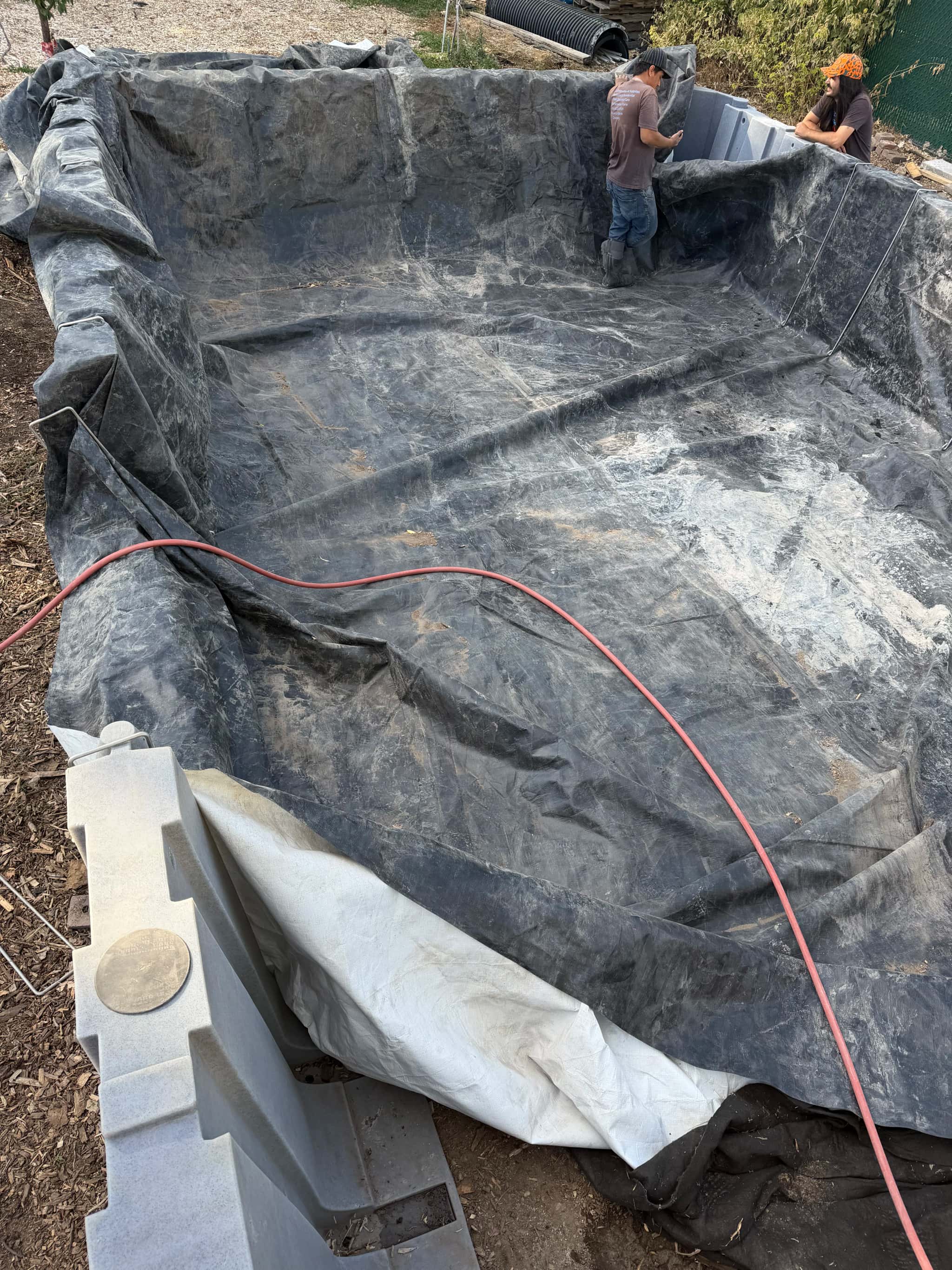 Crew checking liner fit inside pond basin before final anchoring and edge securing