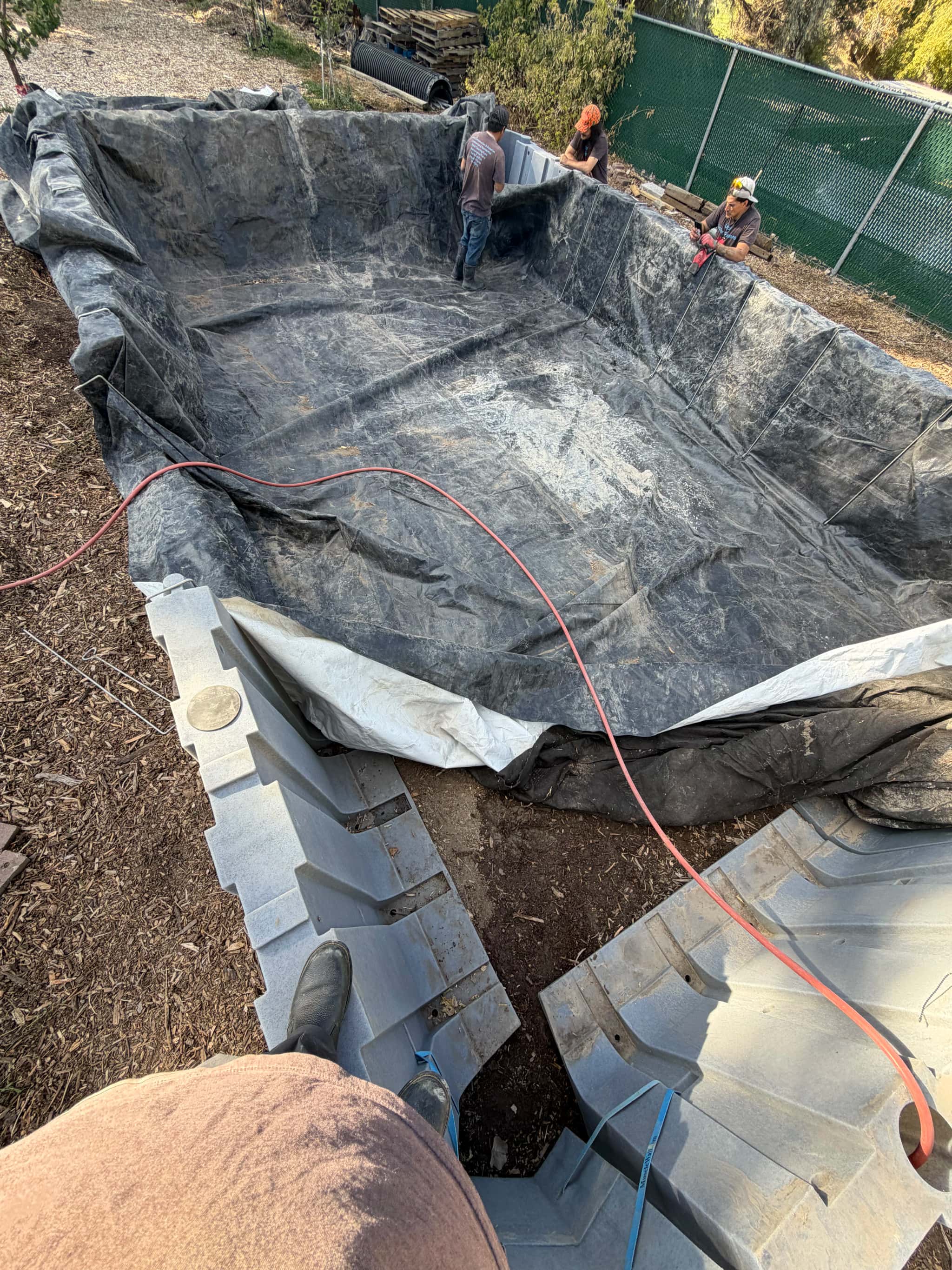 Pond liner fit and trimmed after positioning, ready for seam and edge finishing