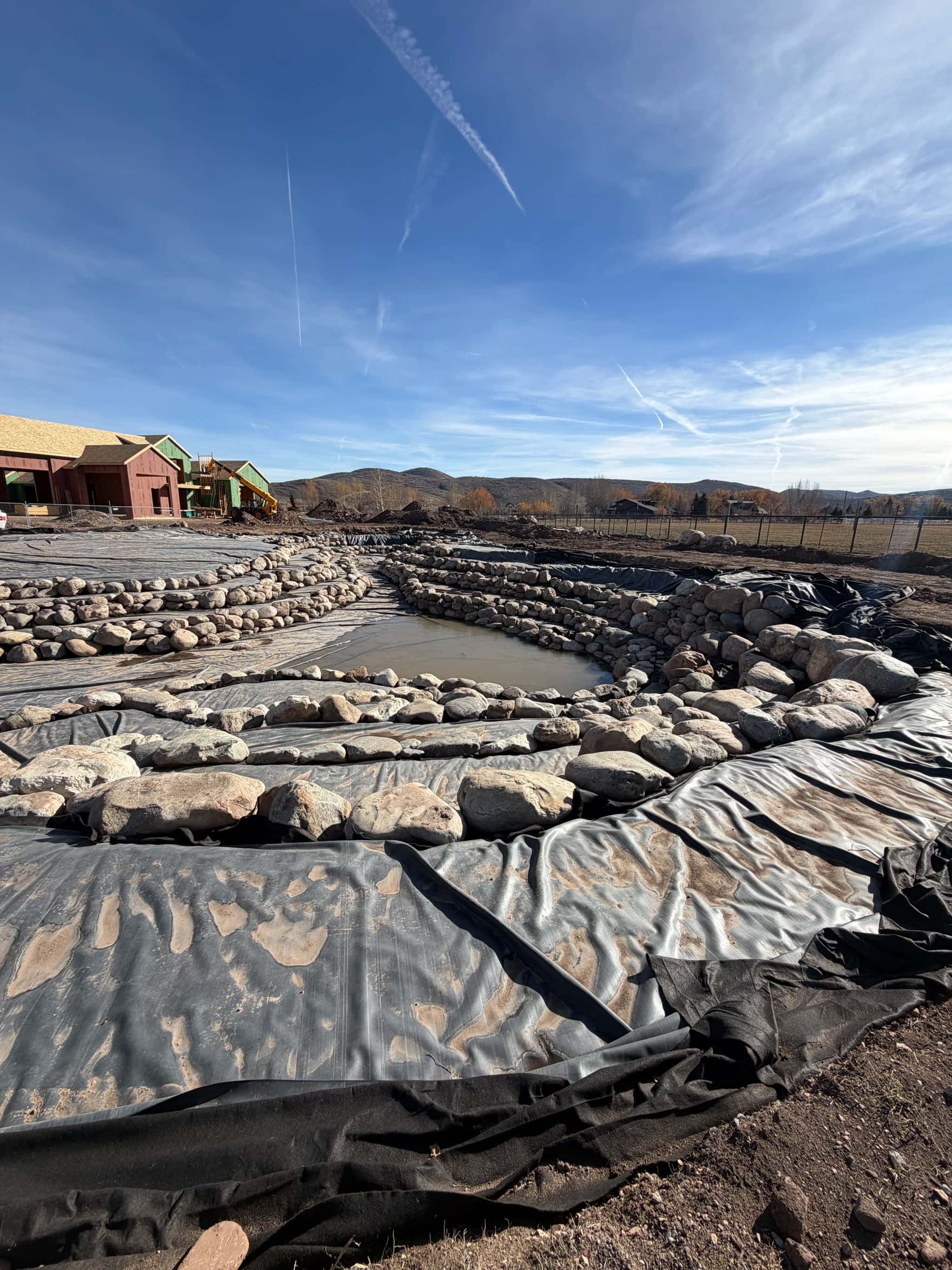 Large pond build with EPDM liner and protective underlayment staged before rockwork