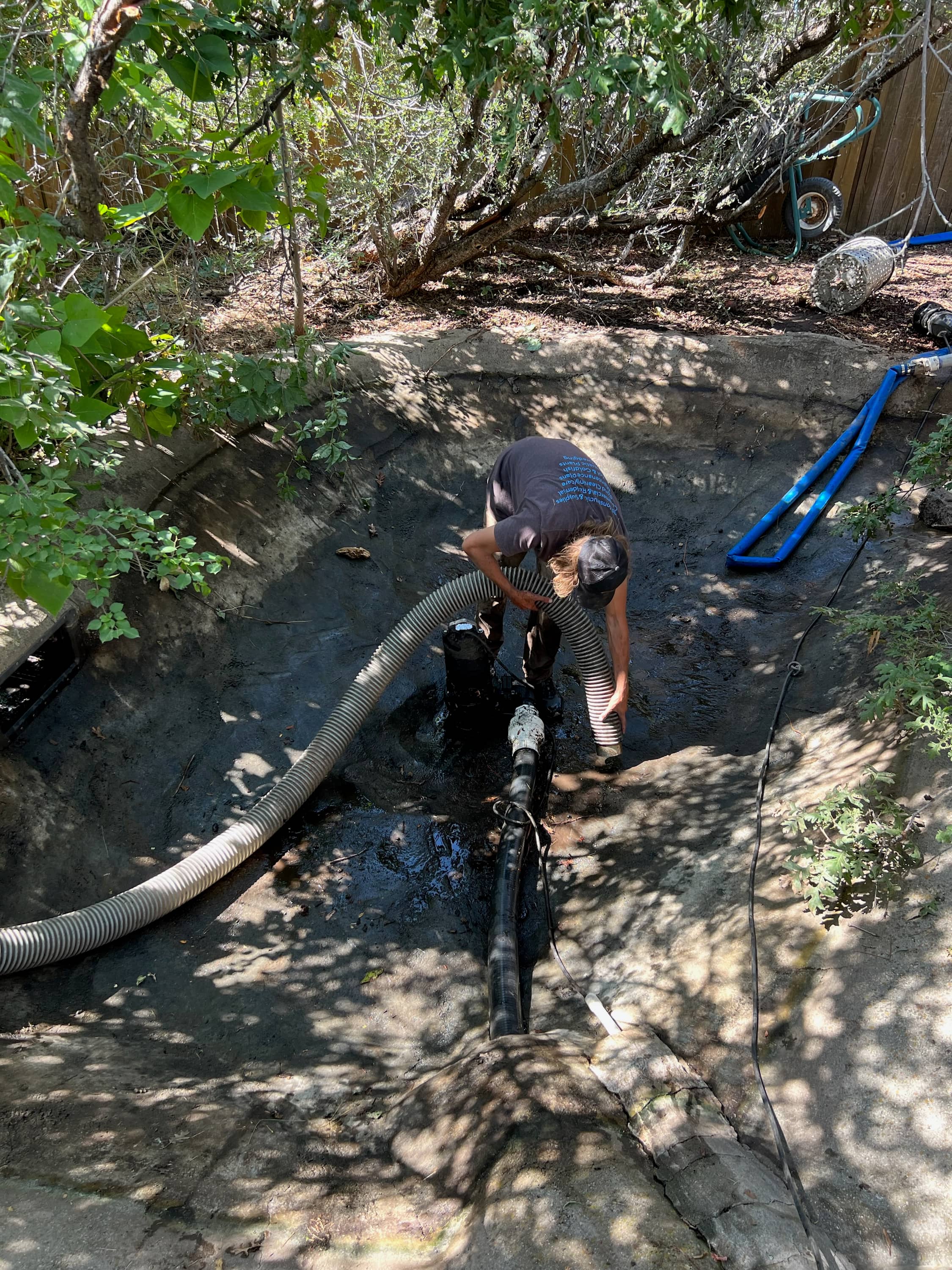 Technician performing pond vacuum service with non-invasive cleaning approach