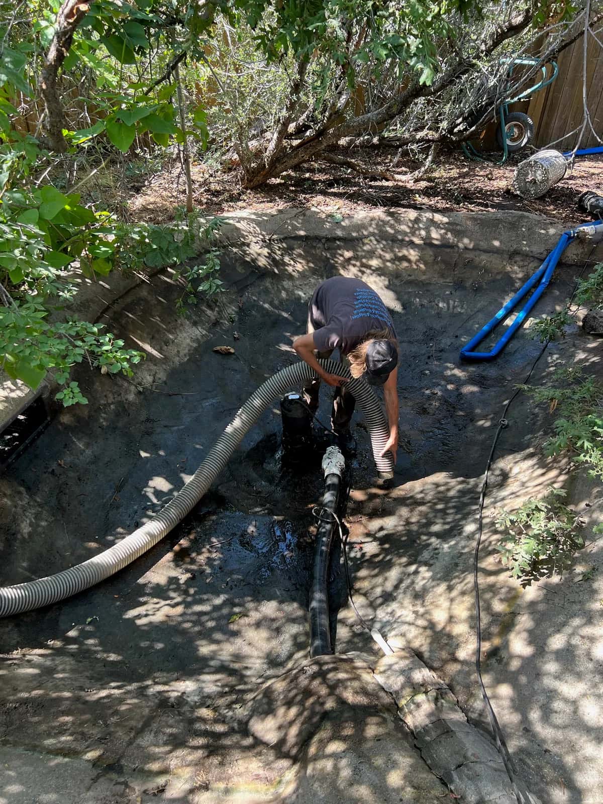 Technician performing pond vacuum service with non-invasive cleaning approach