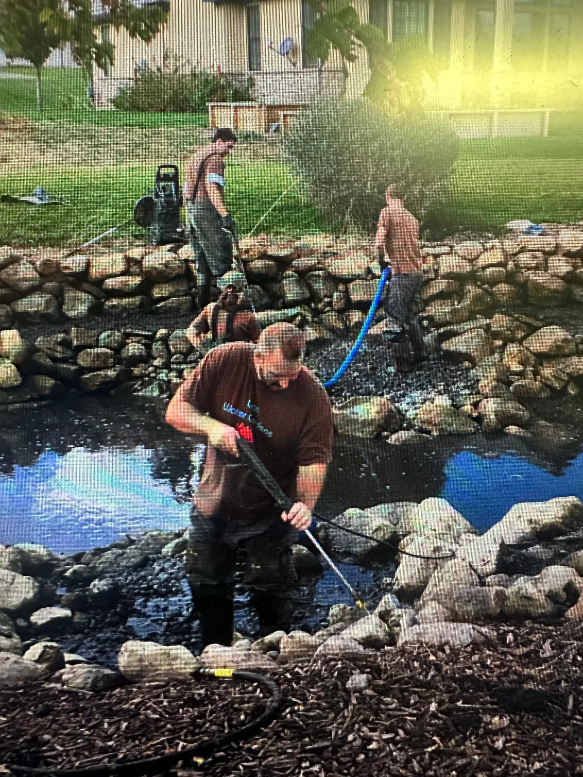 Pressure washing rockwork during pond cleaning service